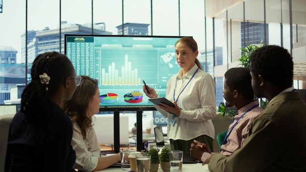 People analyzing financial charts and graphs on a large screen in a modern office setting, highlighting the collaboration and expertise involved in economic forecasting.