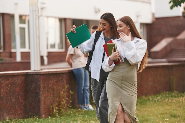 A student happily receiving an acceptance letter from a university. The background shows a college campus with other students walking around, creating a lively and celebratory atmosphere.