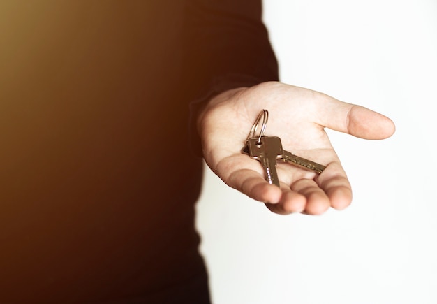 A close-up of a hand holding house keys, with a blurred background showing a 