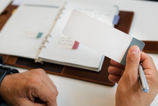 A close-up shot of hands organizing various documents such as a driver's license, bank statement, and a social security card, symbolizing the preparation required for filing an unclaimed property claim. A pen is placed nearby, ready for signing forms.